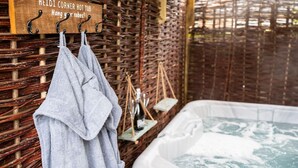 A wooden sign with the text "HEIDI CORNER HOT TUB Hang your robes!" and a towel hanging on a rack.