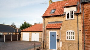 A two-story house with a red-tiled roof, a blue front door, and a garage.