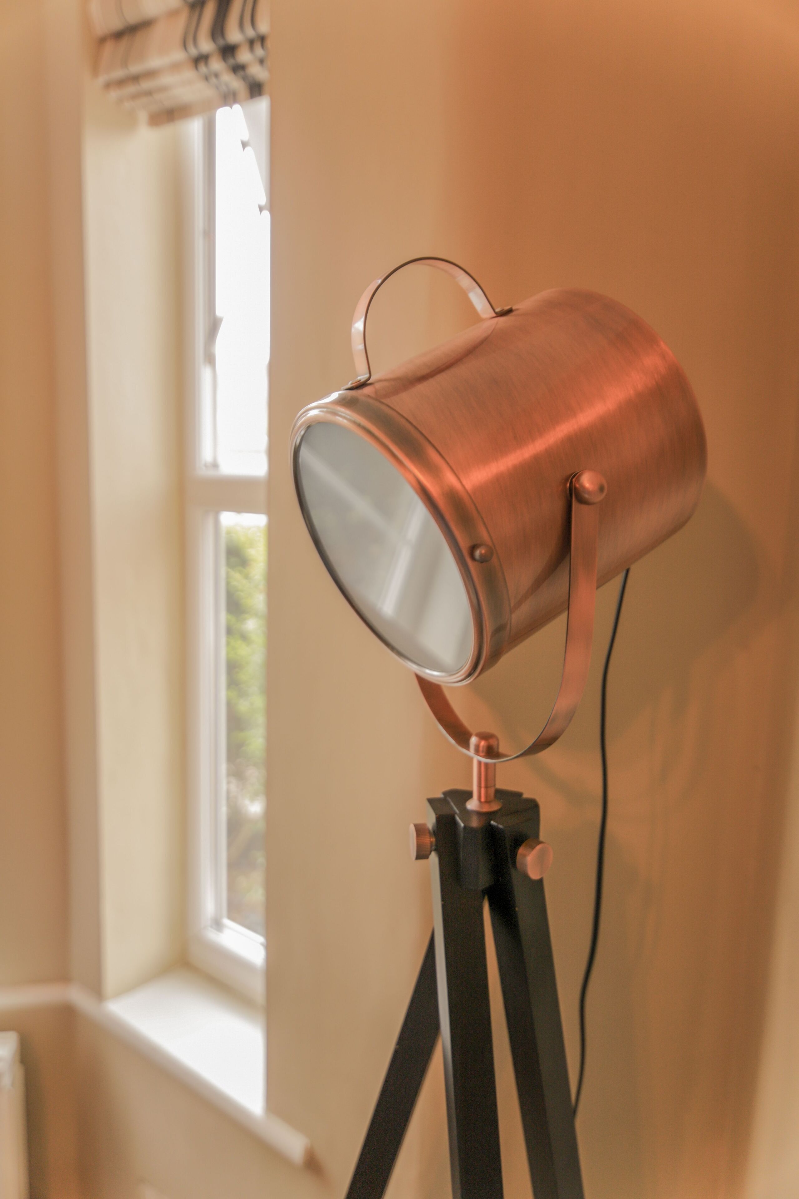 Eine messingfarbene Stehlampe auf Stativ.