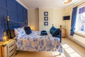 A bedroom with a bed, a dresser, a lamp, and a window.