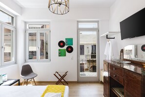 A modern bedroom with a bed, a chair, a dresser, and a television.