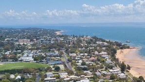 Une ville côtière avec des immeubles résidentiels, une plage et des bateaux sur l’eau.