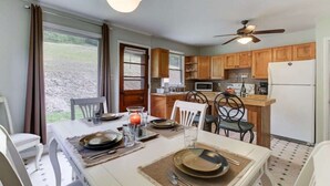 A compact kitchen with wooden cabinets, a dining table set for four, and a ceiling fan. - PET FRIENDLY COTTAGE 3.5 MILES FROM LAKE MOOMAW! (Hot Springs)