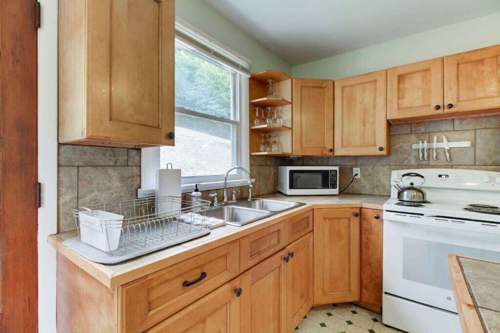 A kitchen with wooden cabinets, a microwave, a kettle, and a sink.