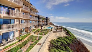 Een strandhotel met meerdere balkons, een zwembad en een prachtig uitzicht op de oceaan.