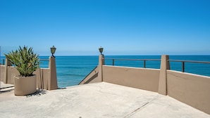 Een balkon met uitzicht op de oceaan, een bloempot en een lantaarnpaal.