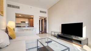 Una sala moderna con un televisor de pantalla plana, una mesa de centro de vidrio y un sofá.