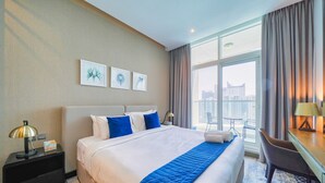 Ein Hotelzimmer mit einem großen Bett, einem Schreibtisch, einem Sessel und einem Balkon mit Blick auf die Stadt.