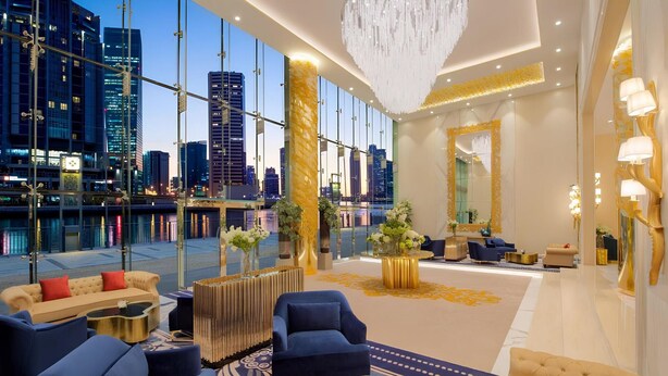 Eine luxuriöse Hotelhalle mit einem großen Fenster, das einen Blick auf die Stadt bietet, stilvollem Mobiliar und einem prächtigen Kronleuchter.
