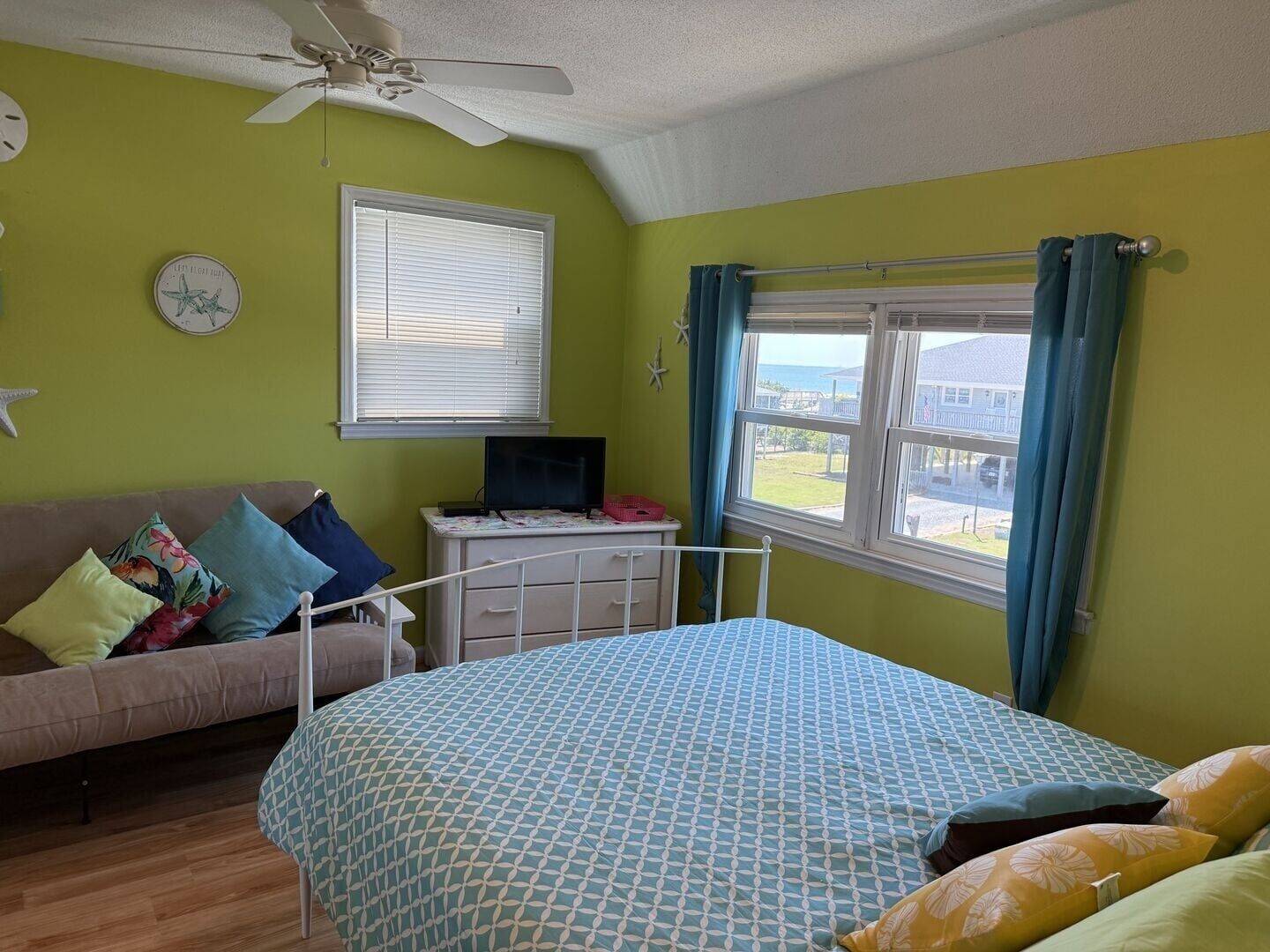 Un dormitorio con cama, escritorio, silla y ventana con cortinas.