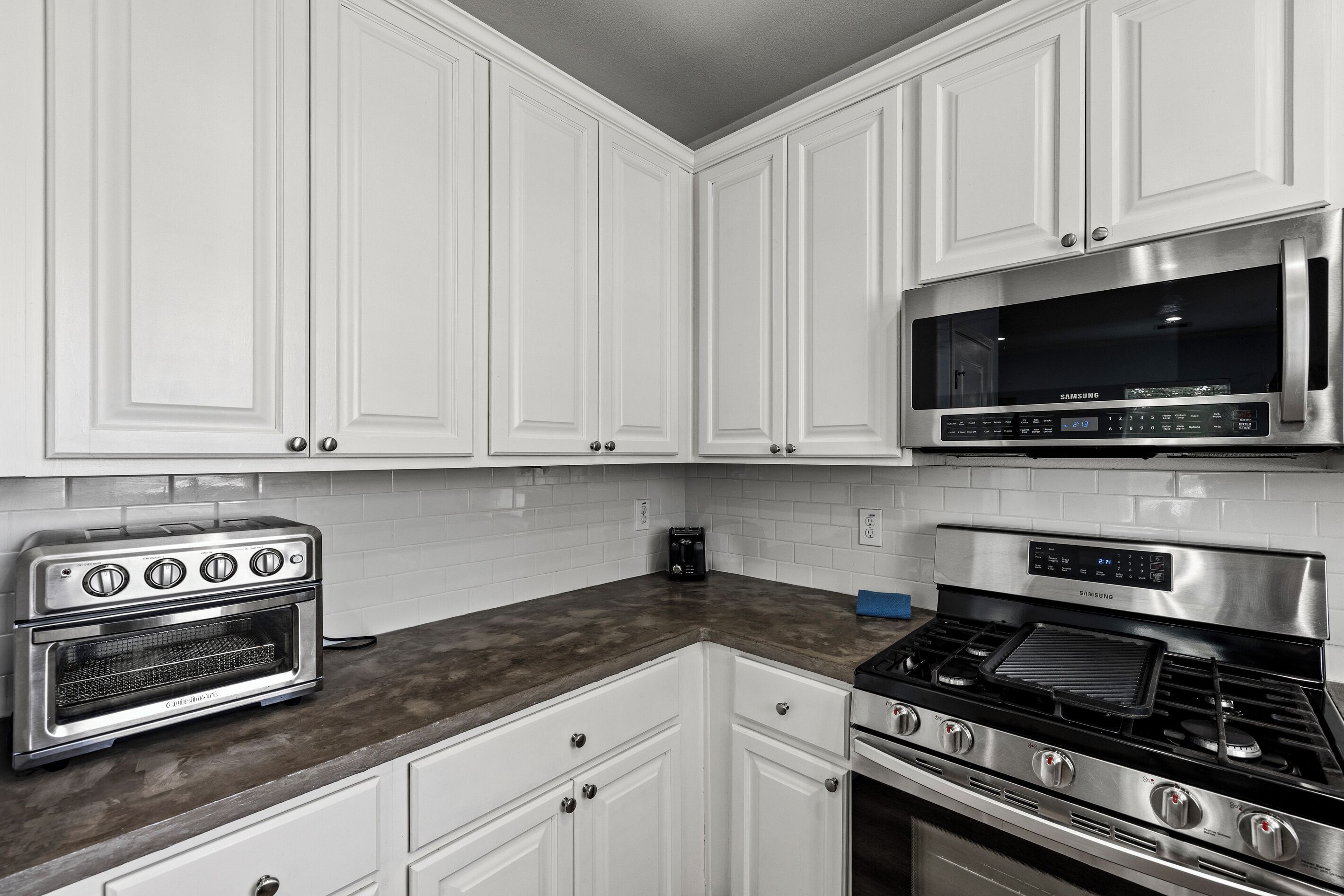A kitchen with white cabinets, a stainless steel microwave, a built-in oven, and a gas stove.