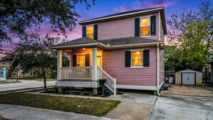 A two-story house with a porch, a garage, and a small shed. - Summer Bliss | Walk to Beach • Master Suite • Bunk Beds • Sleeps 9 (Galveston)