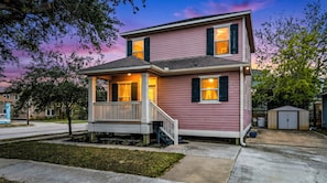 A two-story house with a porch, a garage, and a small shed.