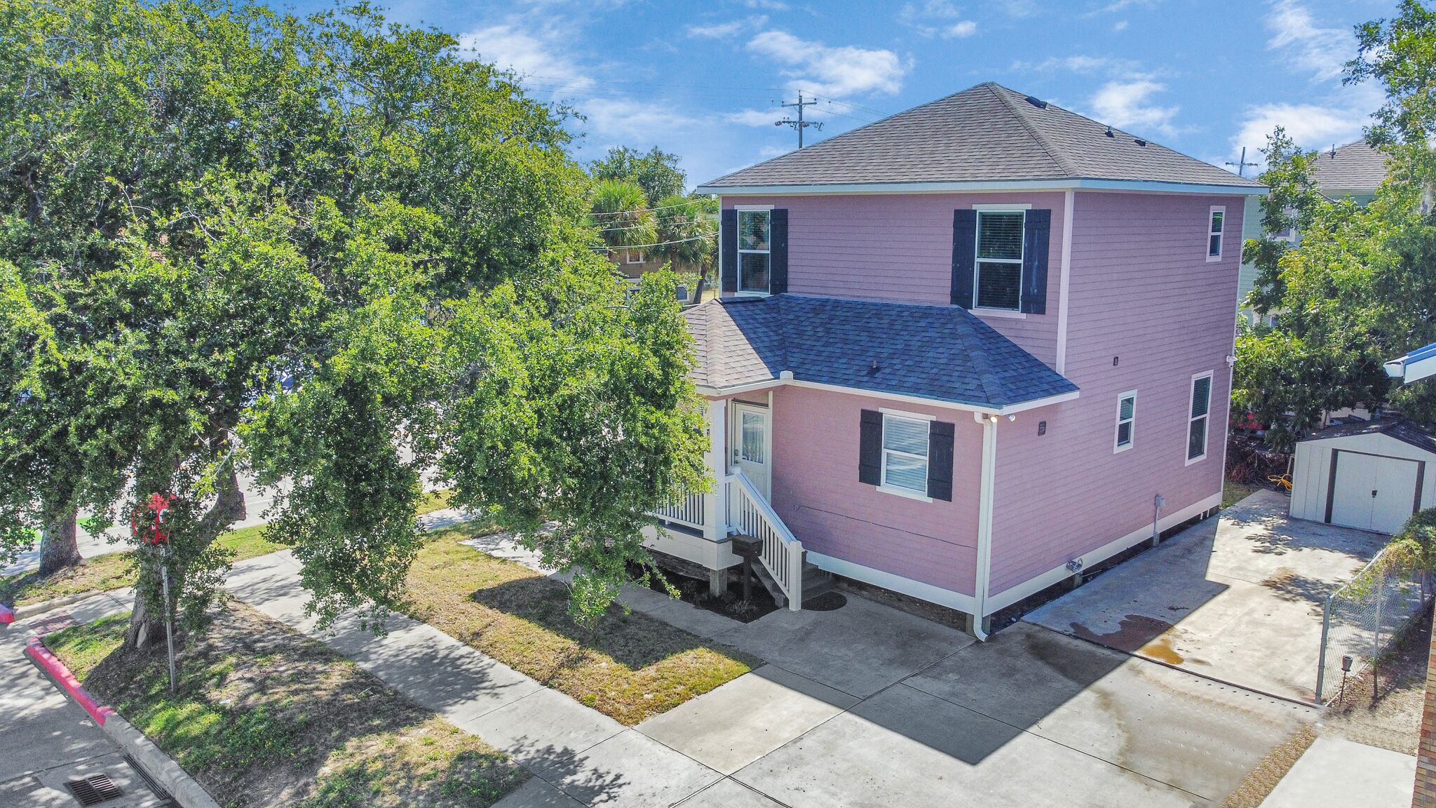 A two-story house with a pink exterior, a front porch, and a garage.