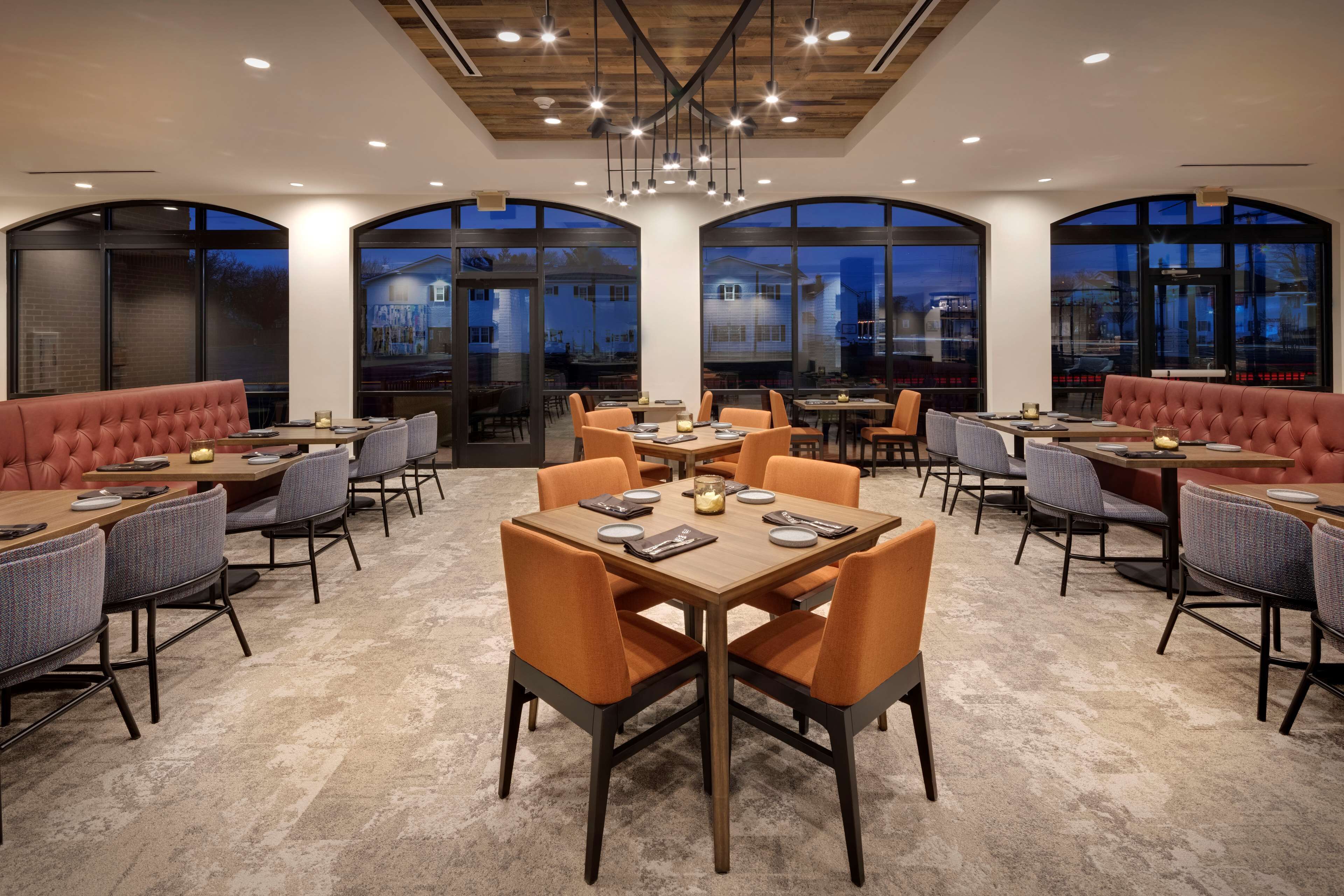 A modern restaurant with high ceilings, large windows, and a mix of seating options including tables and booths.