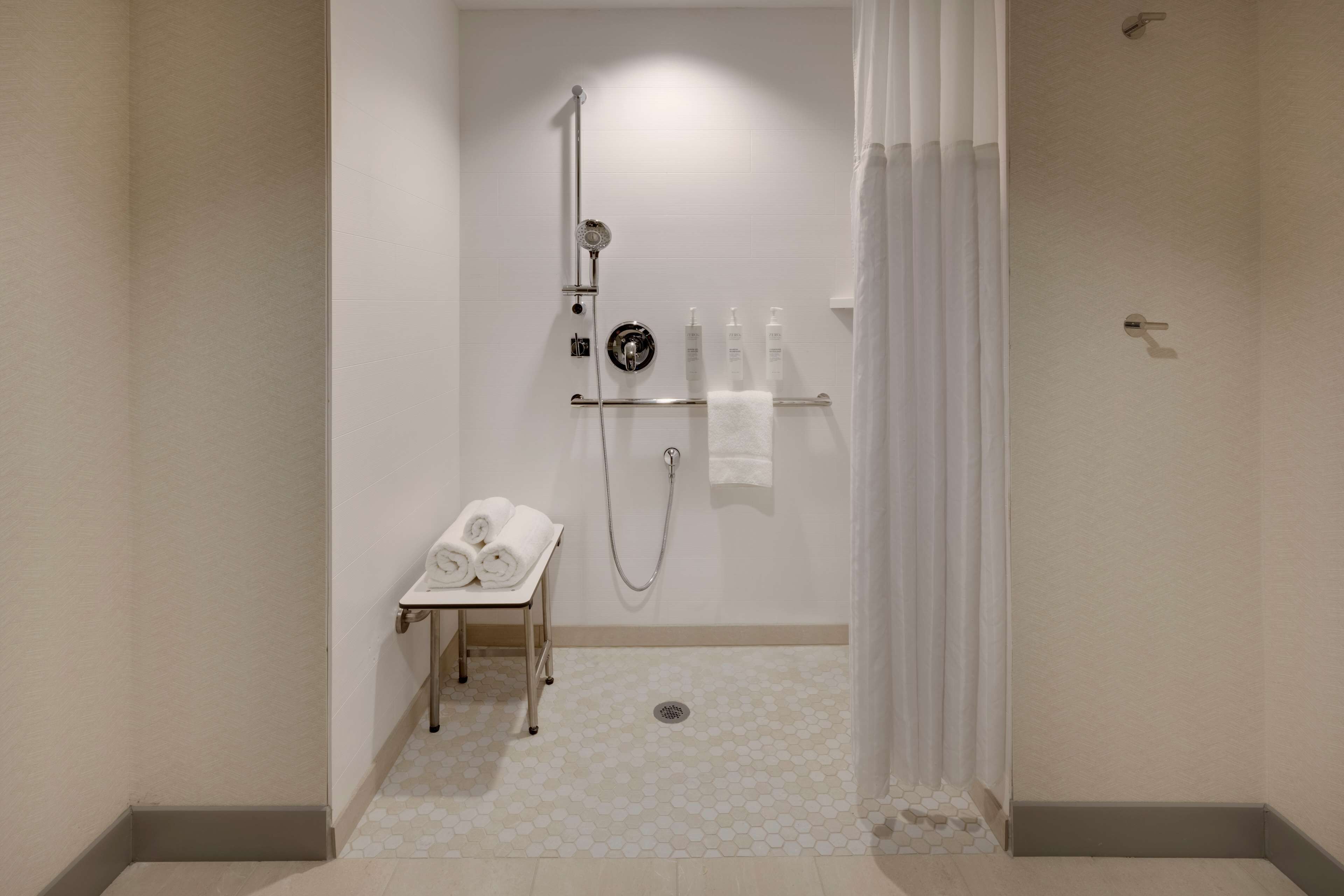 Une salle de bain moderne équipée d’une douche, d’un porte-serviettes et d’une petite table sur laquelle sont posées des serviettes.