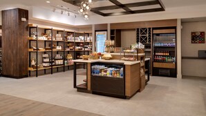 Un espace de vente moderne, doté d’étagères en bois, d’un comptoir central et d’un espace réfrigéré.