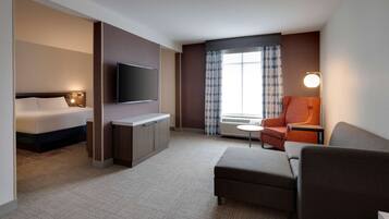 Habitación de hotel con cama, televisor, escritorio, silla y sofá.
