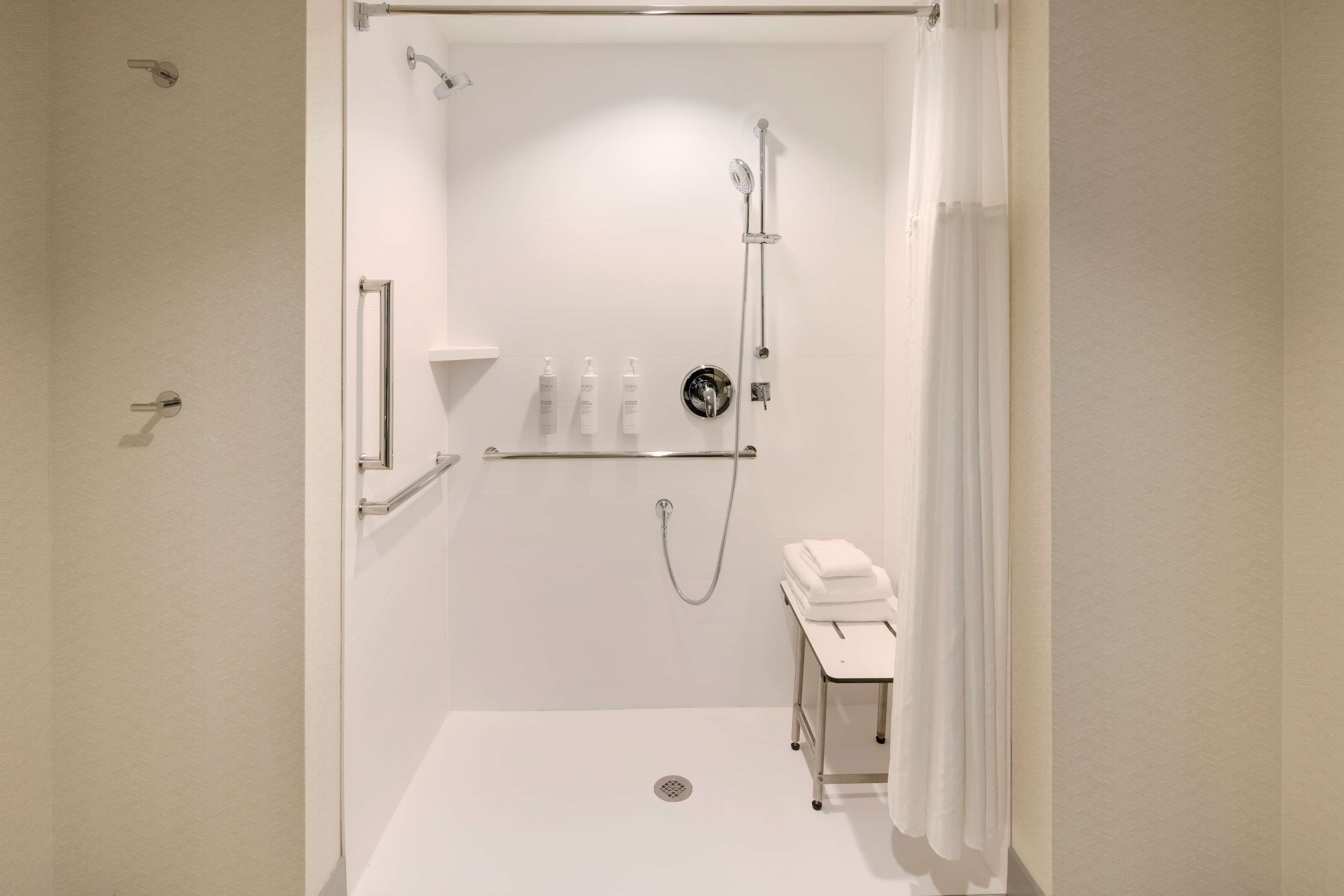 Ein modernes Duschbad mit Handbrause, Wandarmatur und Ablage für Pflegeprodukte.