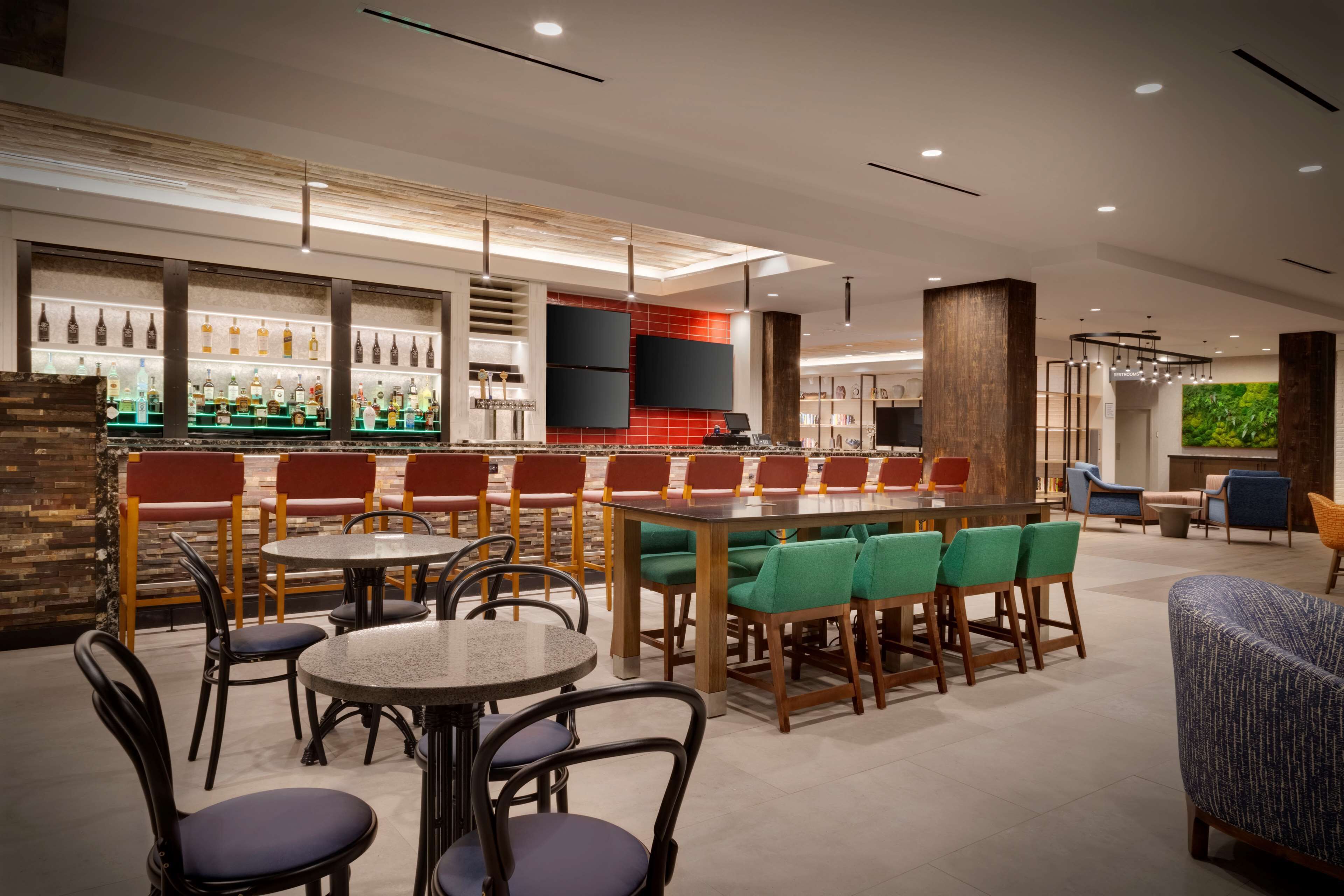 A modern bar area with multiple seating options, including round tables and bar stools.