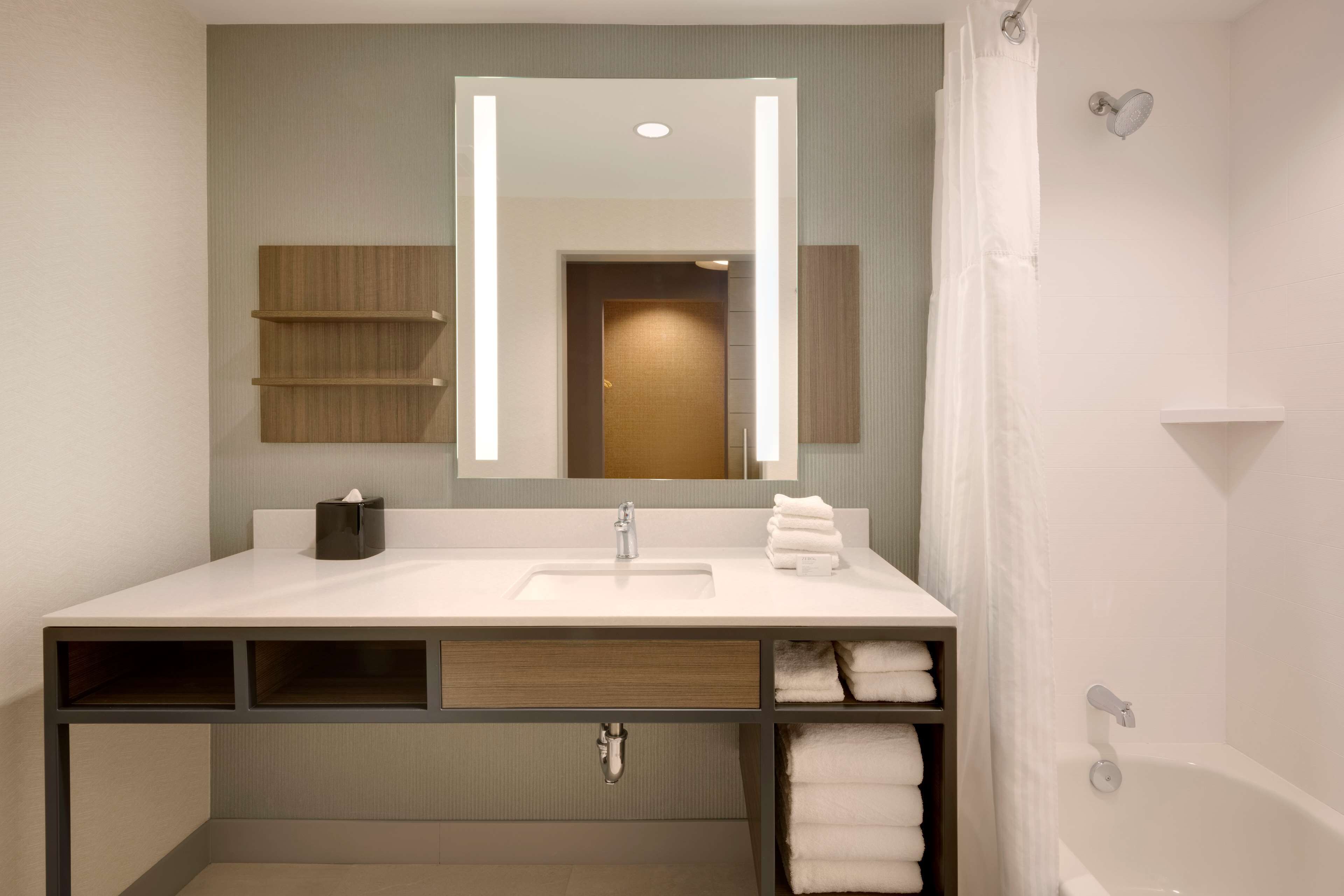 Une salle de bain moderne avec un lavabo blanc, un miroir et une douche.