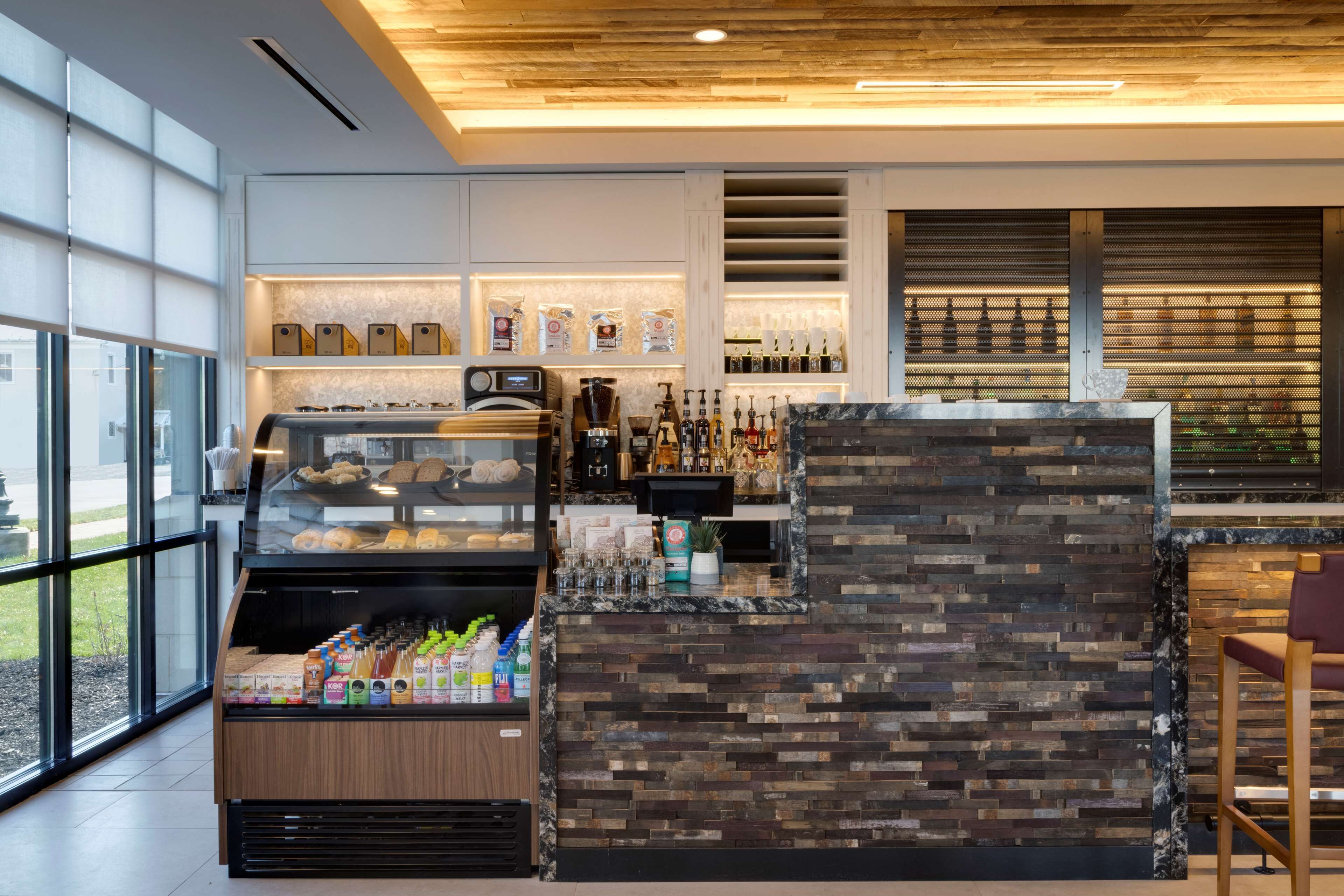 A modern bar area with a stone wall, shelves with beverages, and a coffee display.
