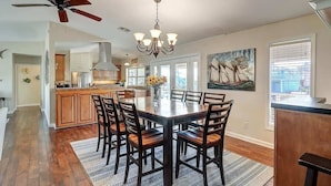 A dining area with a round table, chairs, a chandelier, and a ceiling fan.