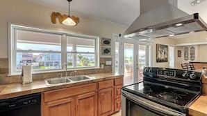 A kitchen with a stove, sink, and wooden cabinets.