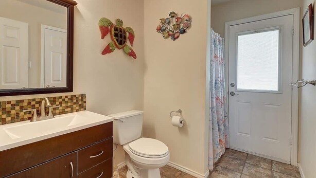 A bathroom with a white toilet, a sink with a mirror, and decorative wall art.