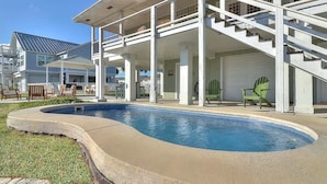 A residential property with a swimming pool, a covered patio, and a staircase leading to a garage.