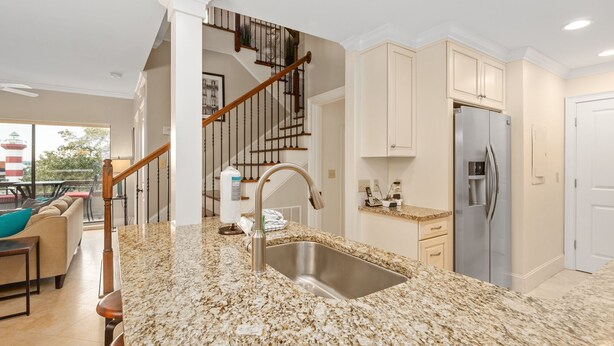 Una cocina moderna con encimeras de granito, electrodomésticos de acero inoxidable y una escalera de madera.