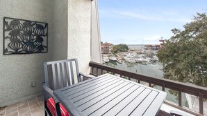 Un balcón con mesa y sillas, con vista a un puerto deportivo con barcos y edificios.