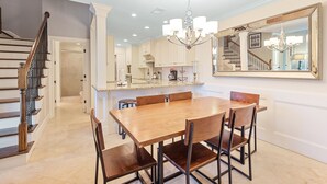 Un comedor amplio con una mesa y sillas de madera, un espejo grande y una escalera que sube a otro nivel.