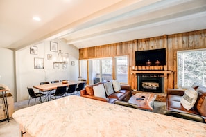 A spacious living room with a fireplace, leather sofas, a dining area, and a large marble kitchen island. - Lift Condo: Walk To Slopes, Downtown (Breckenridge)