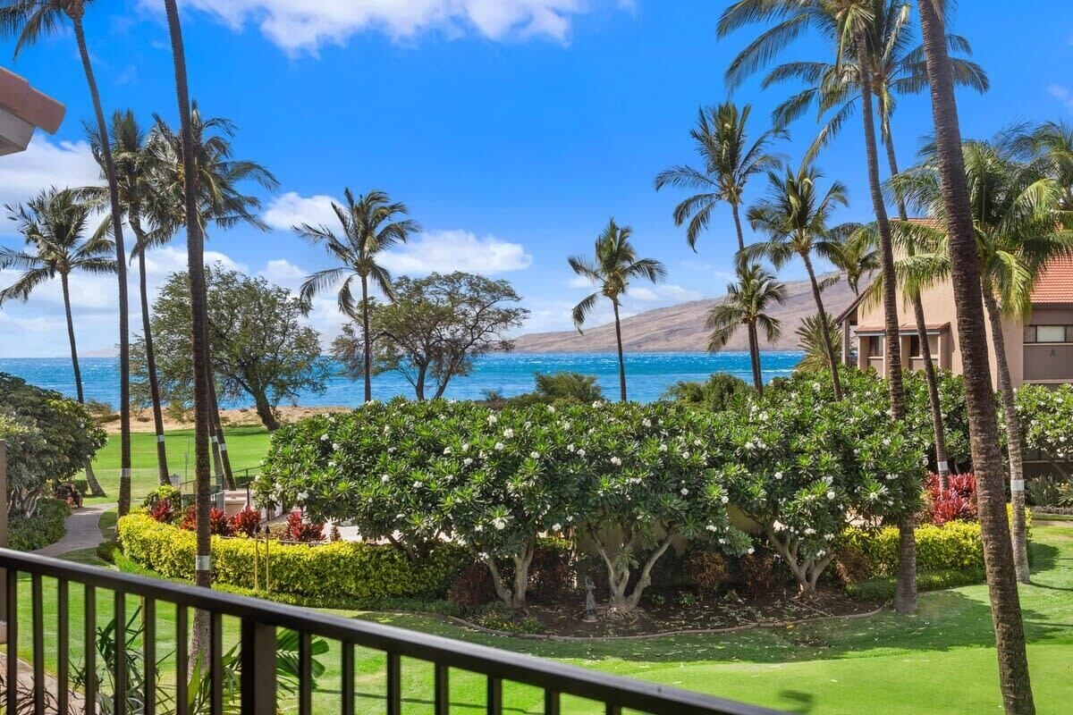 Um resort tropical com vista para o oceano, palmeiras e um jardim bem cuidado.