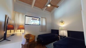 A bedroom with two beds, a chair, a TV, and a ceiling fan. - Magnificent Sunsets and Beachfront at Luana Kai (Kihei)