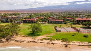 A coastal resort with multiple buildings, a beach, and a tennis court.
