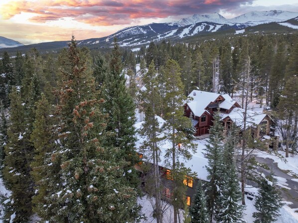 A lodge surrounded by snow-covered trees and mountains, with a clear view of the landscape.