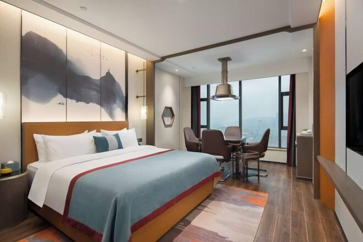 Ein modernes Hotelzimmer mit einem großen Bett, einem Schreibtisch und Blick auf die Stadt.