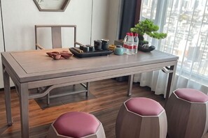 Una mesa de comedor con taburetes, una silla, una bandeja con salsas, una planta en maceta y una ventana con vistas.