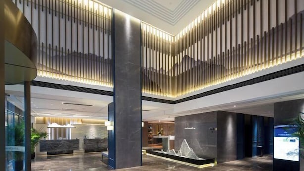 Een moderne hotel lobby met een receptiebalie, een zithoek en een decoratieve waterpartij.
