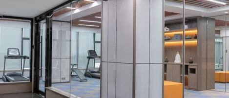 Centro de fitness moderno com equipamentos de exercício, parede espelhada e piso estampado.