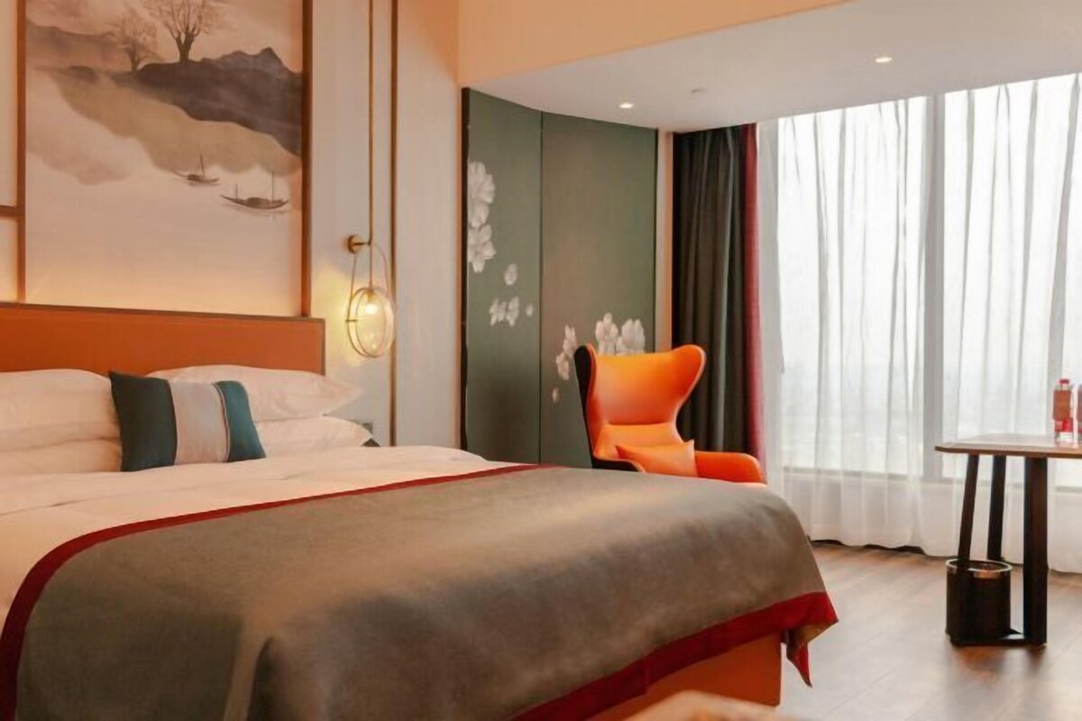 Une chambre d’hôtel avec un lit, une chaise, une table et un tableau au mur.