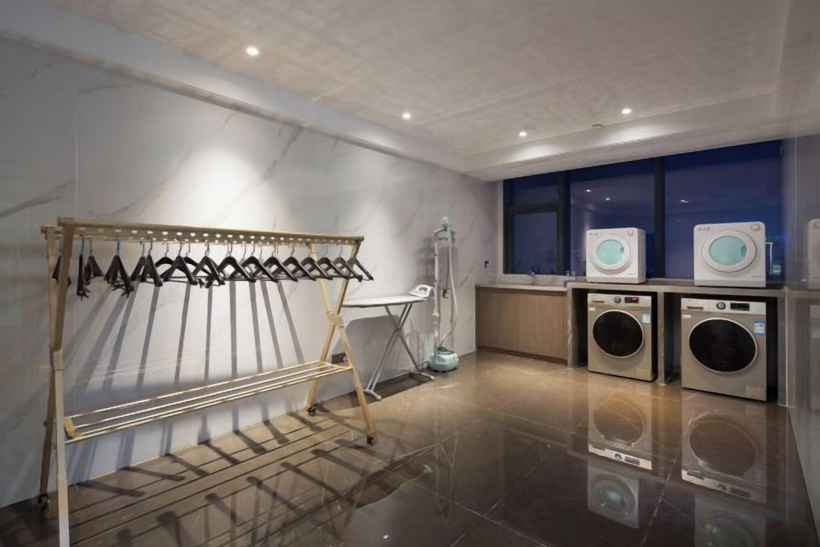 A laundry area with a drying rack, two washing machines, and a folding station.