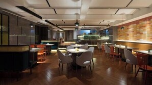 Een modern restaurant met houten vloeren, witte en oranje stoelen, en een centraal gelegen eetgedeelte.