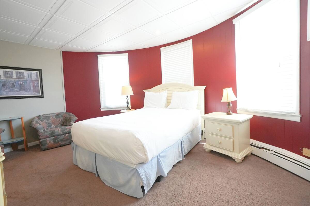 Une chambre à coucher avec un lit, des tables de chevet, une chaise et un tableau encadré au mur.