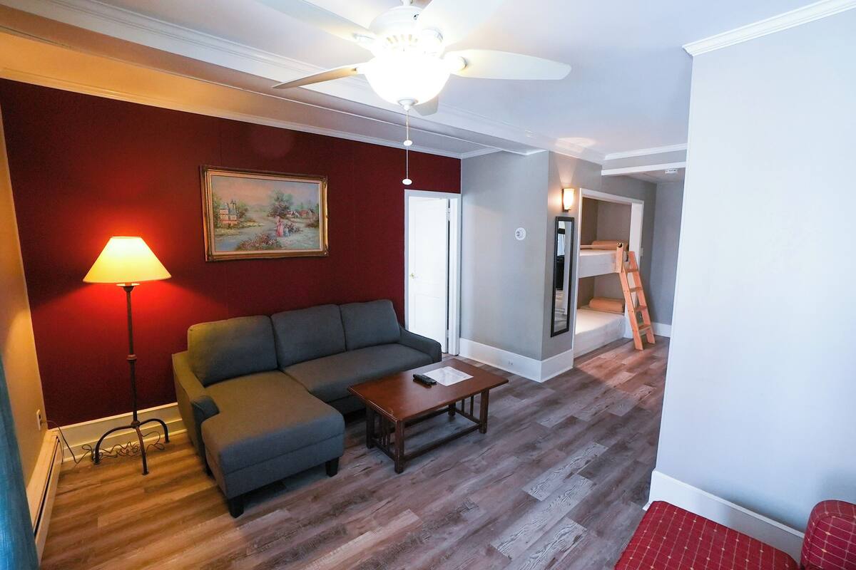 Un salon avec un canapé, une table basse, une lampe et un ventilateur de plafond.