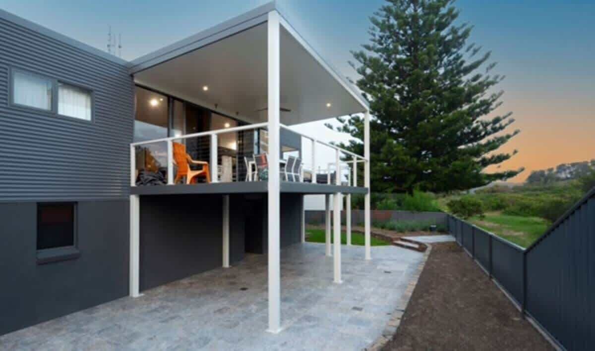 A modern building with a covered outdoor area, a balcony, and a view of the surrounding landscape.