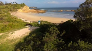 A coastal beach with a sandy shore, a wooden walkway, and a signpost. - Jenkins Galwad-y-Mor | Beachfront Tomakin (TOMAKIN)