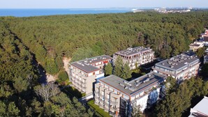 Zona residencial con modernos edificios de apartamentos rodeados de un bosque frondoso.